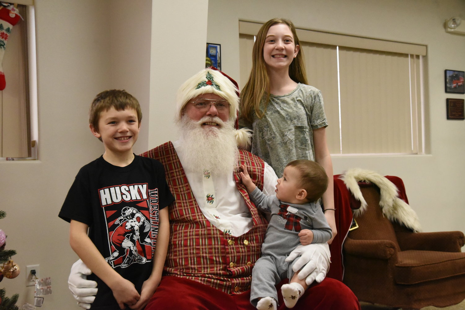 Myles Slay, 9, and 12-year-old Catelynn Sexton poses for a photo with Santa while 8-month-old Camden Sexton was fascinated by the jolly old man’s beard.