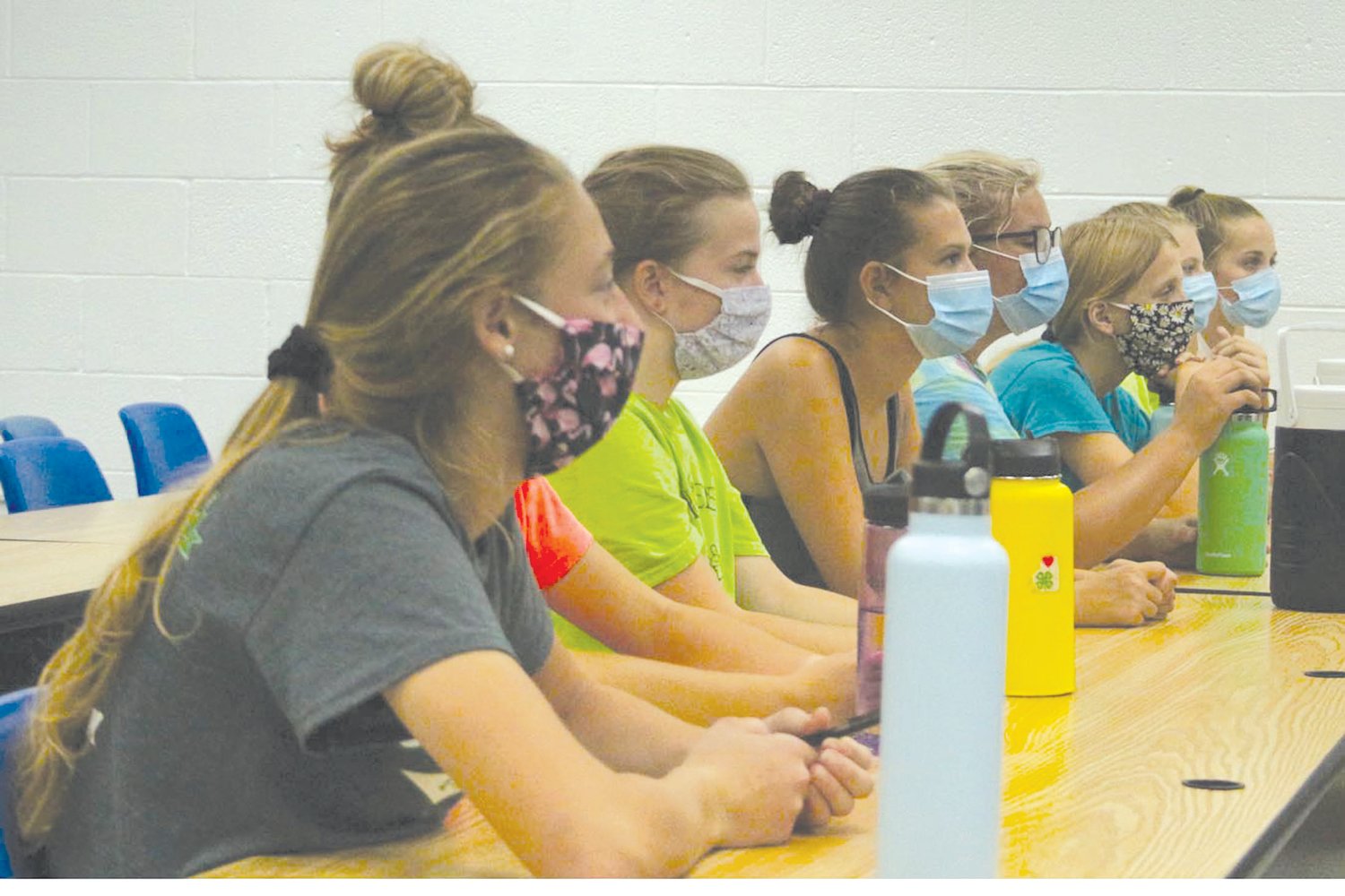 Members of the Lone Tree volleyball team don their masks while listening to co-coach Sonda Prybil’s instructions in a classroom.