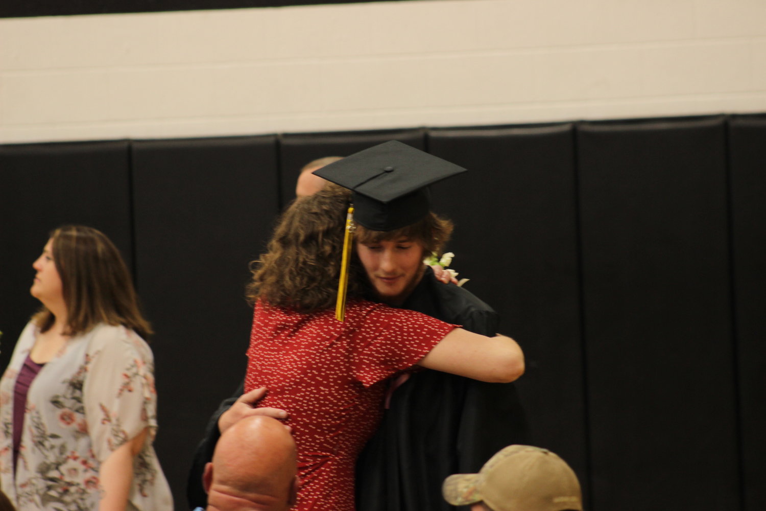 A senior embraces a hug with their mother after being handed their diploma.