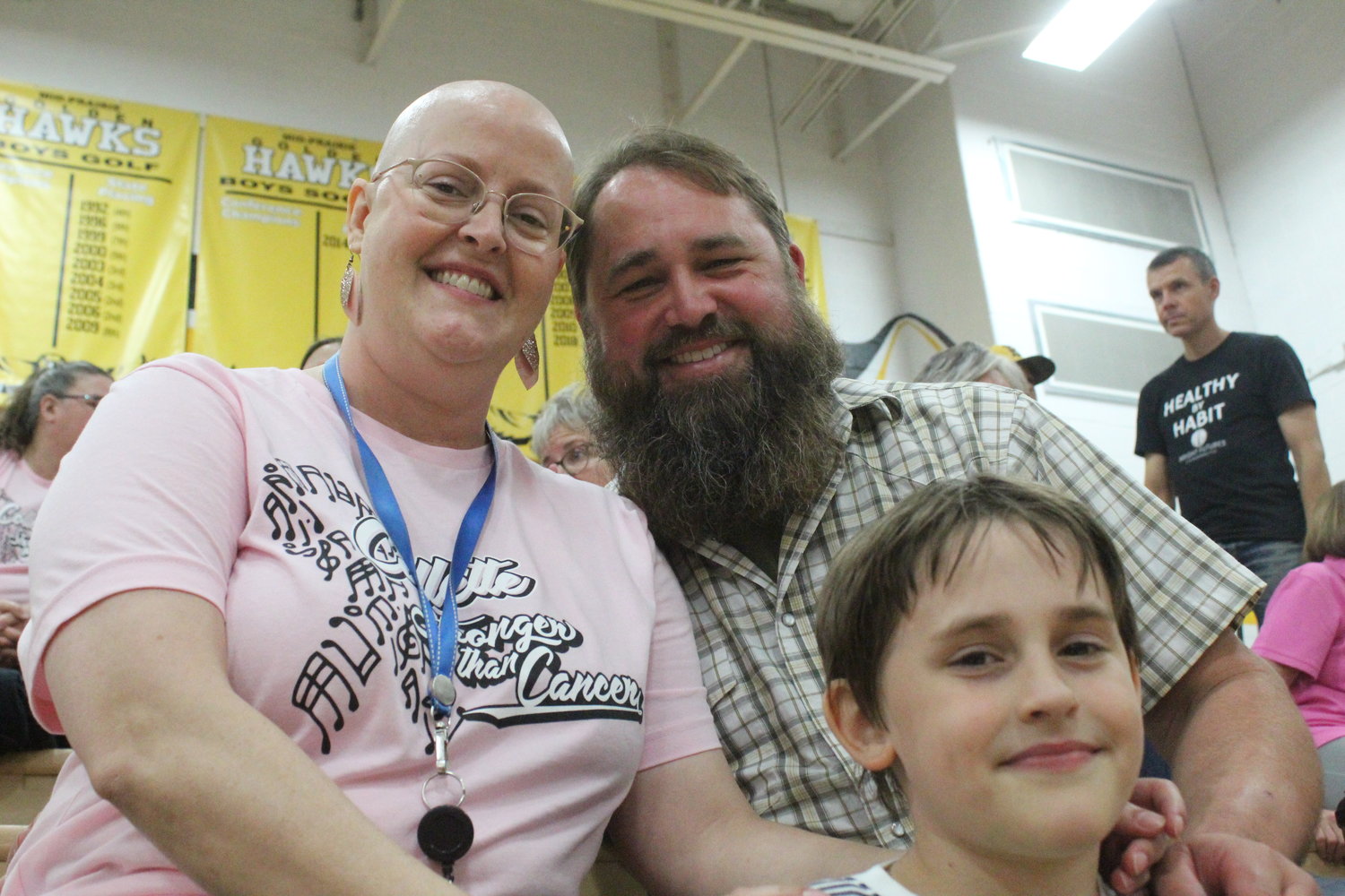 Collette McClellen, a Mid-Prairie music teacher who is undergoing treatment for breast cancer, enjoys the Golden Hawks "Dig Pink" volleyball night with her husband, Matthew, and one of her children, Adric. She also has a daughter, Fiona.