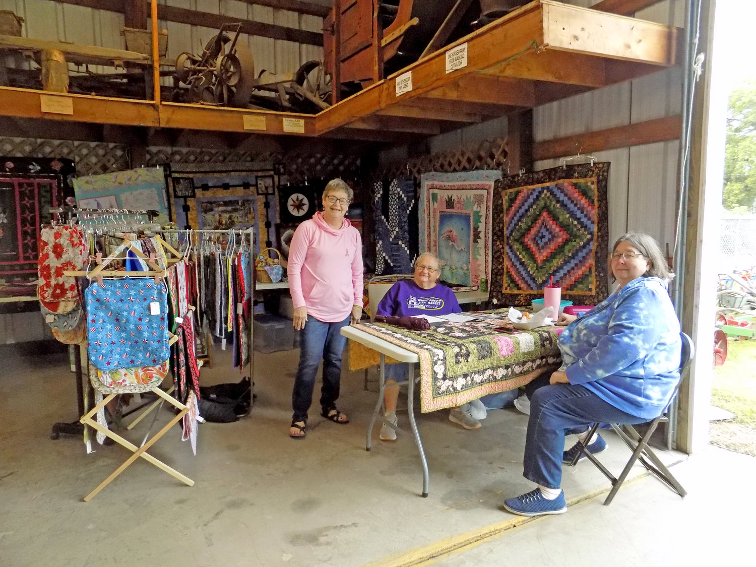 Joyce Schrock, Ann Yotty, and Colette Yoder sold colorful quilts, table linens, washcloths, and bowl cozies inside the Ag Museum.