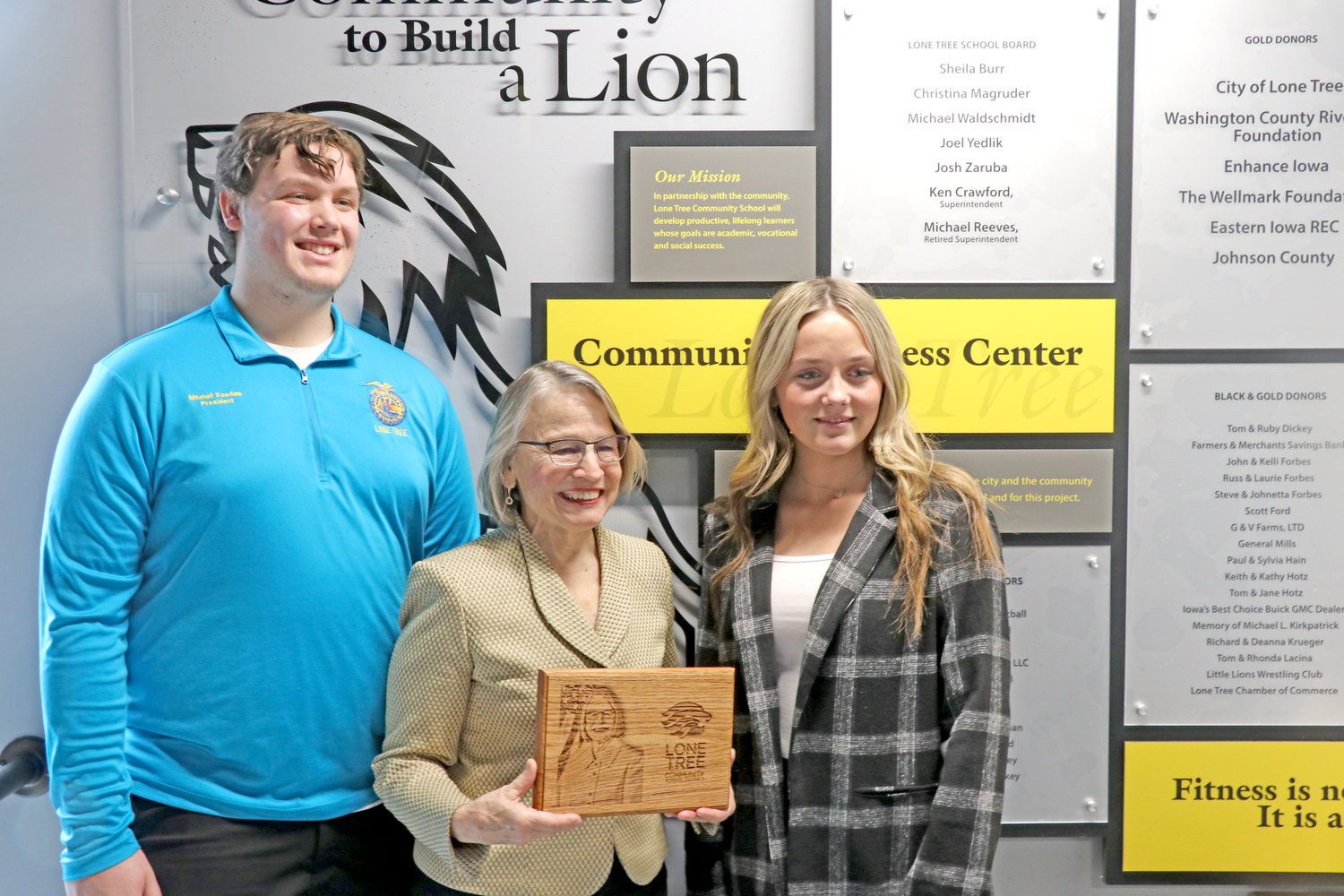Students Mitchell Koedam and Lila Bell lead Rep. Miller-Meeks on a school tour.  At their last stop at the Community Wellness Center, they presented her with a plaque laser-engraved with her likeness and the school’s logo.