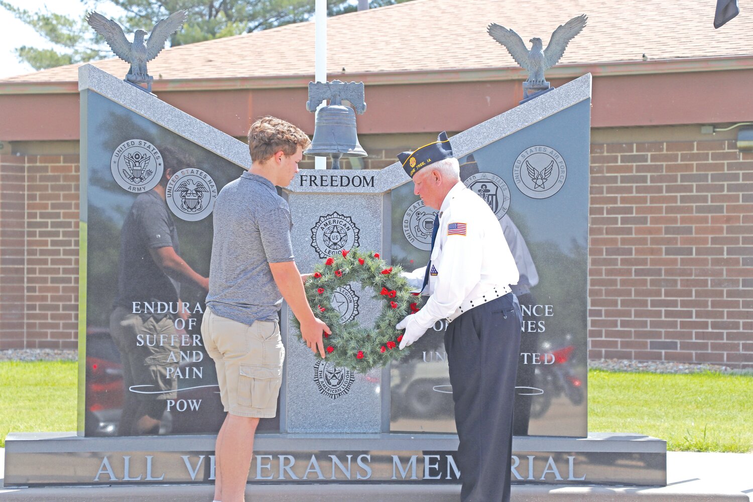 A Lone Tree resident assists the Lone Tree American Legion Color Guard in laying the wreath before the ceremonial shots on Memorial Day.